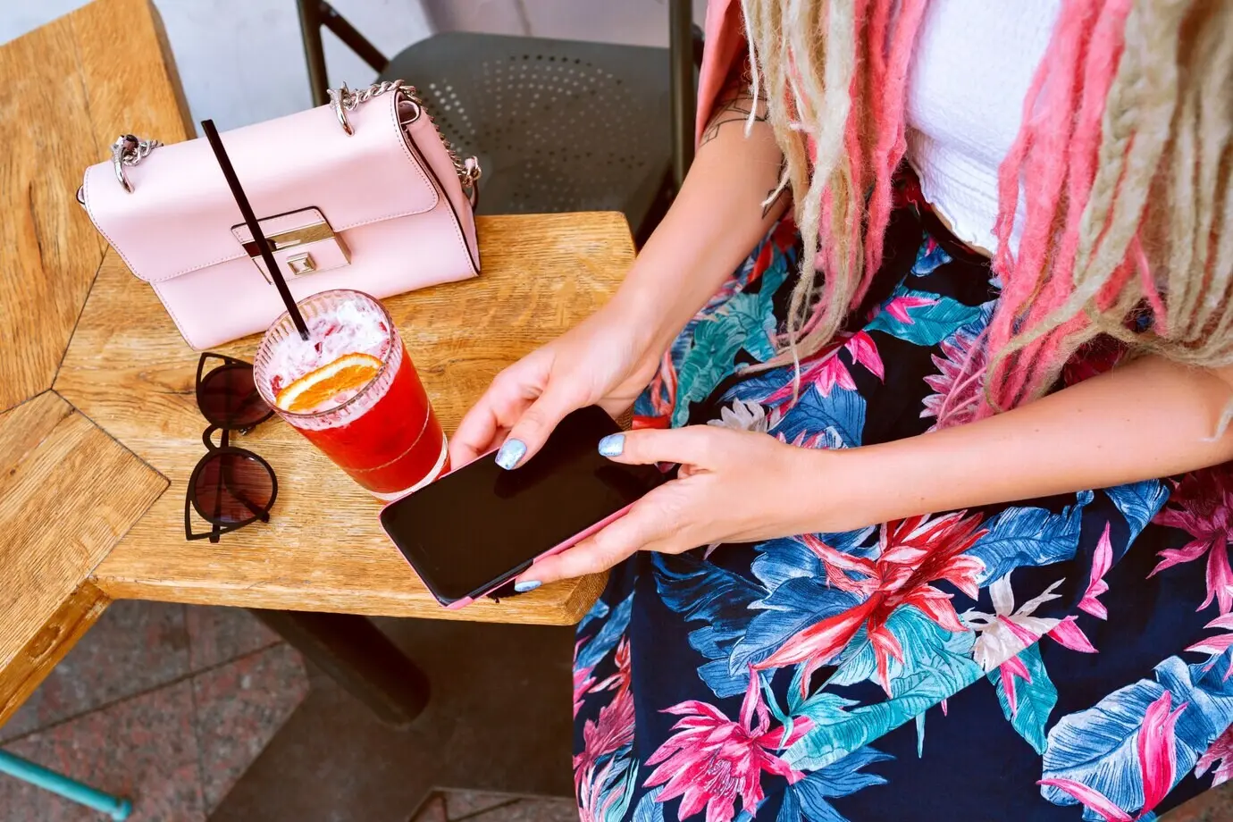 Eine Frau hält ihr Smartphone und trinkt leckere Limonade.
