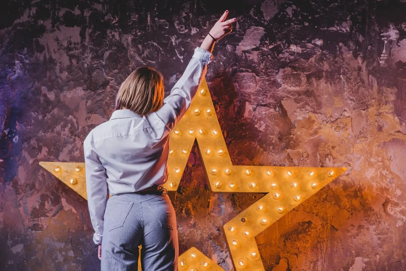 Nicht erkennbare Frau, die mit zwei Fingern auf einen Stern zeigt.